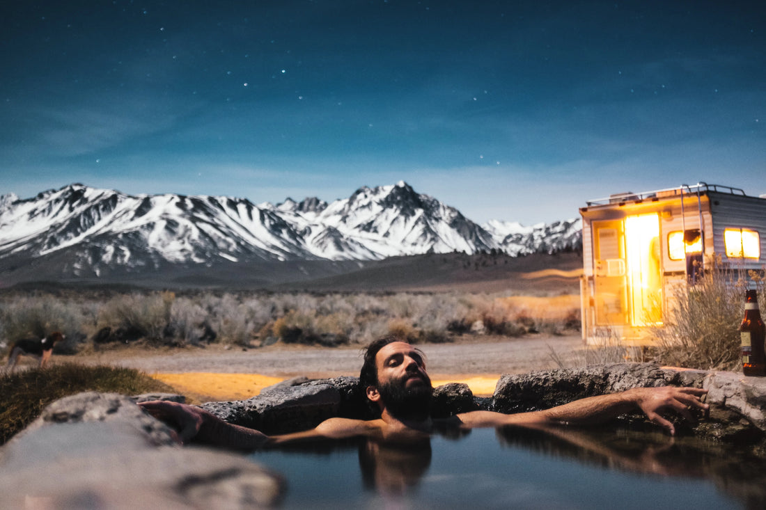 A man relaxing in an ice bath beside his trailer, showcasing resilience and connection with nature.