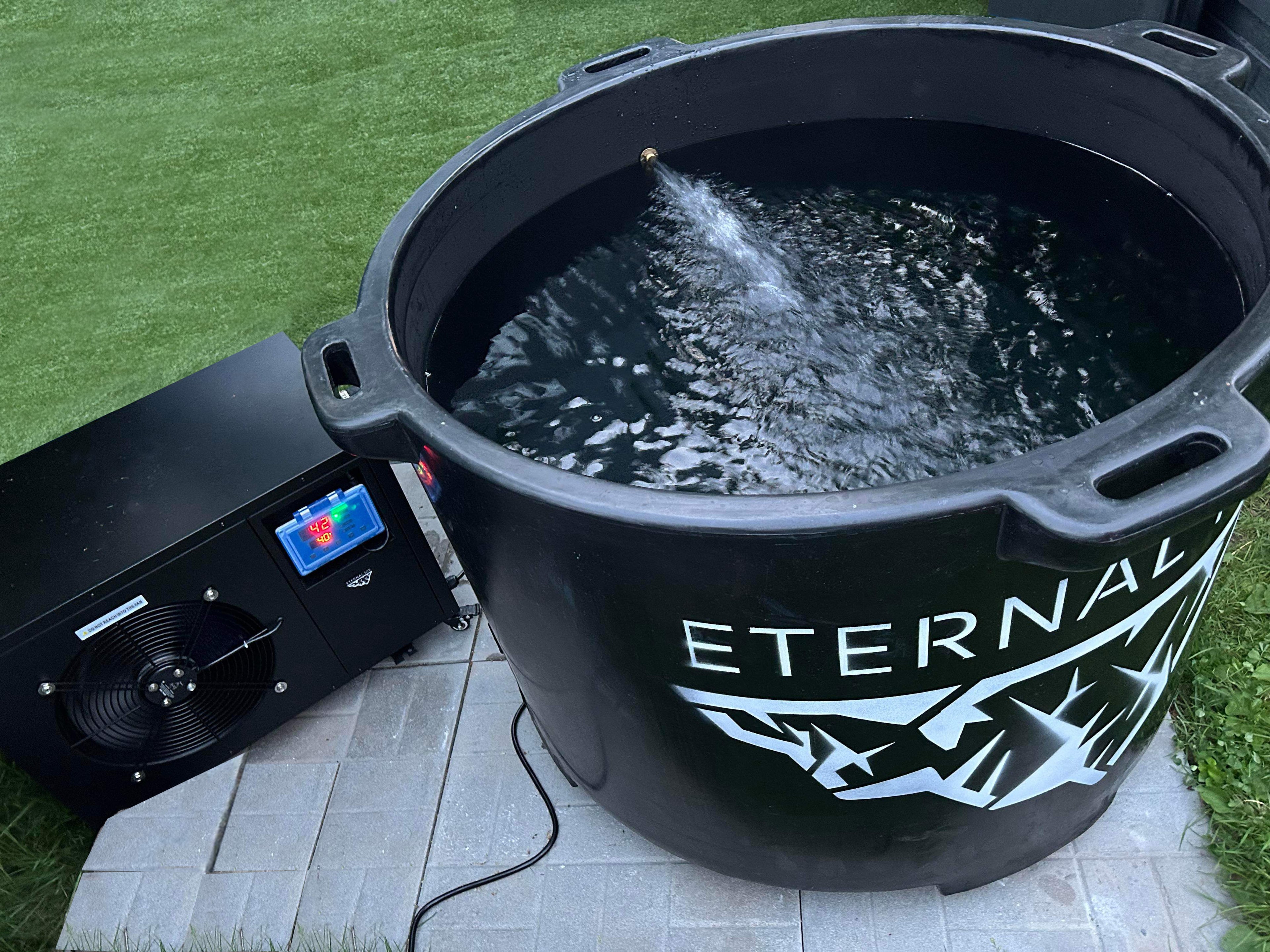 Une image présentant, dans une cour arrière, le bain de glace Eternal Ice HD Pro et son compagnon, le refroidisseur Eternal Ice Power Chiller, conçus pour des expériences de refroidissement sans pareille. Le bain de glace brille avec une finition polie, tandis que le refroidisseur vibre avec puissance, promettant un approvisionnement durable en eau glacé.