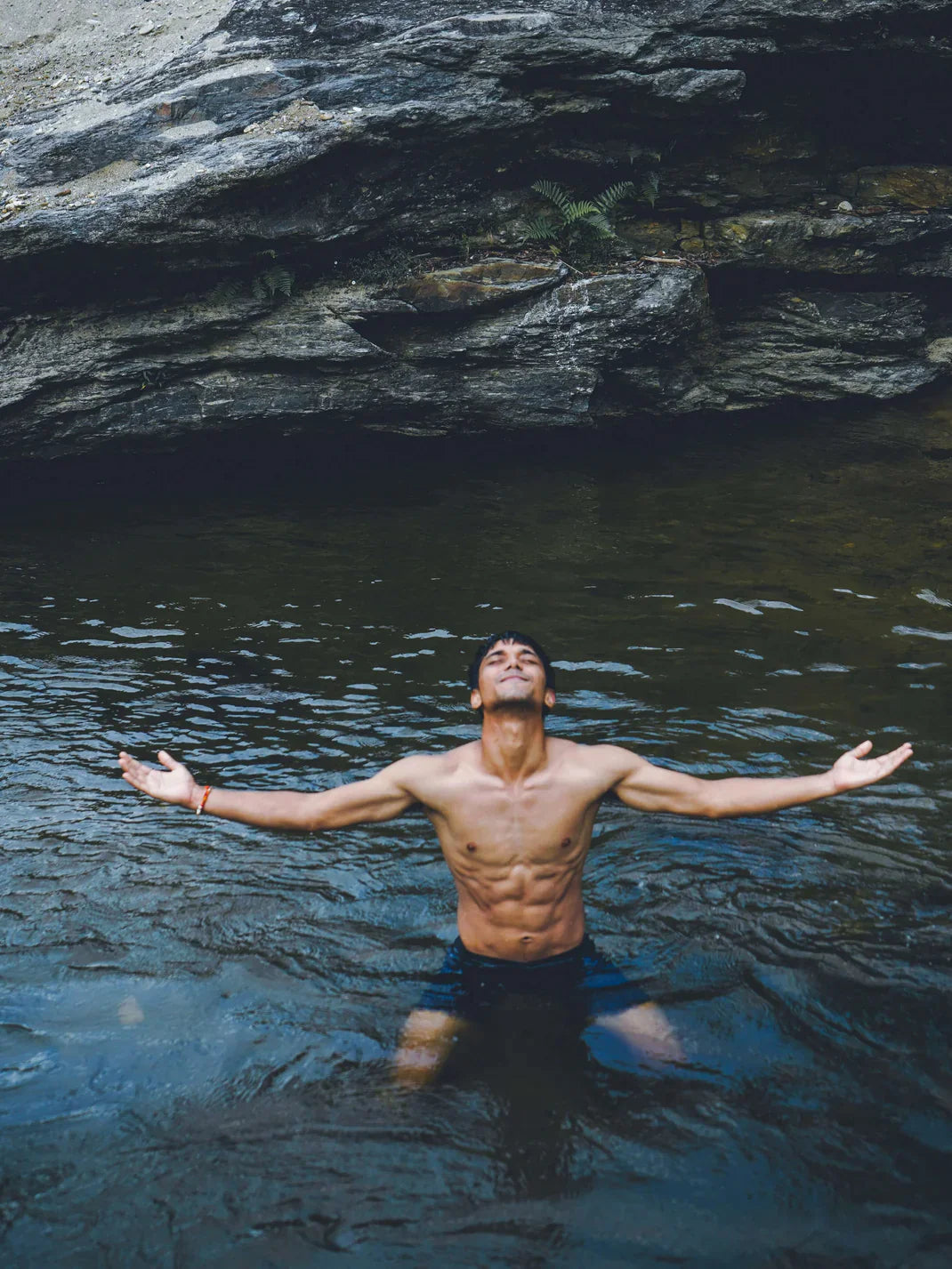 Un jeune homme immergé dans une rivière glaciale, incarnant la résilience et la vitalité au milieu des éléments de la nature.